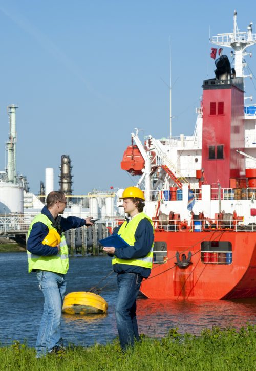 Dockers discussing an issue with a moored ship in an industrial harbor